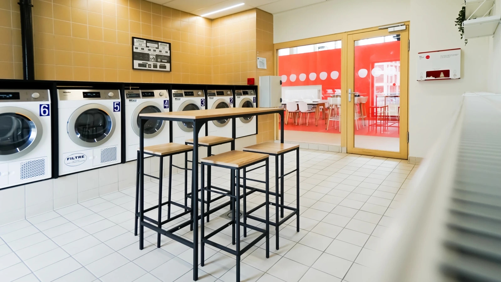 Buanderie d'établissement installée par Lavri, appareils professionnels alignés et espace de pliage